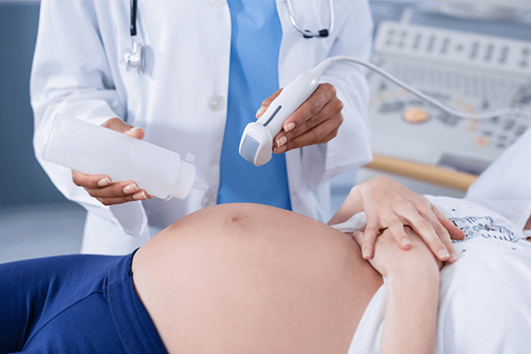 Doctor performing a prenatal ultrasound scan on a pregnant patient